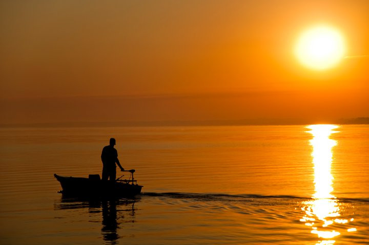 Horgász a Balatonon kora reggel Nap felkeltében